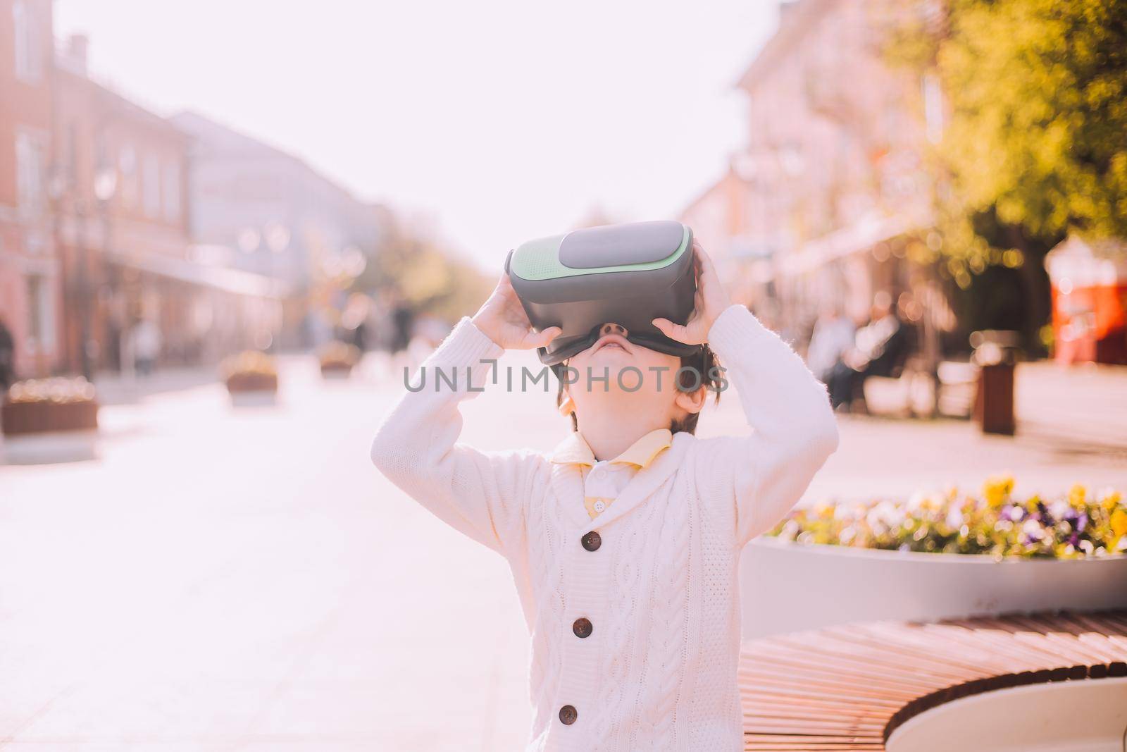 A boy is playing virtual reality glasses on the street . Modern gadgets. Children's games. The choice of virtual glasses. An article about virtual glasses. Modern children. Copy Space