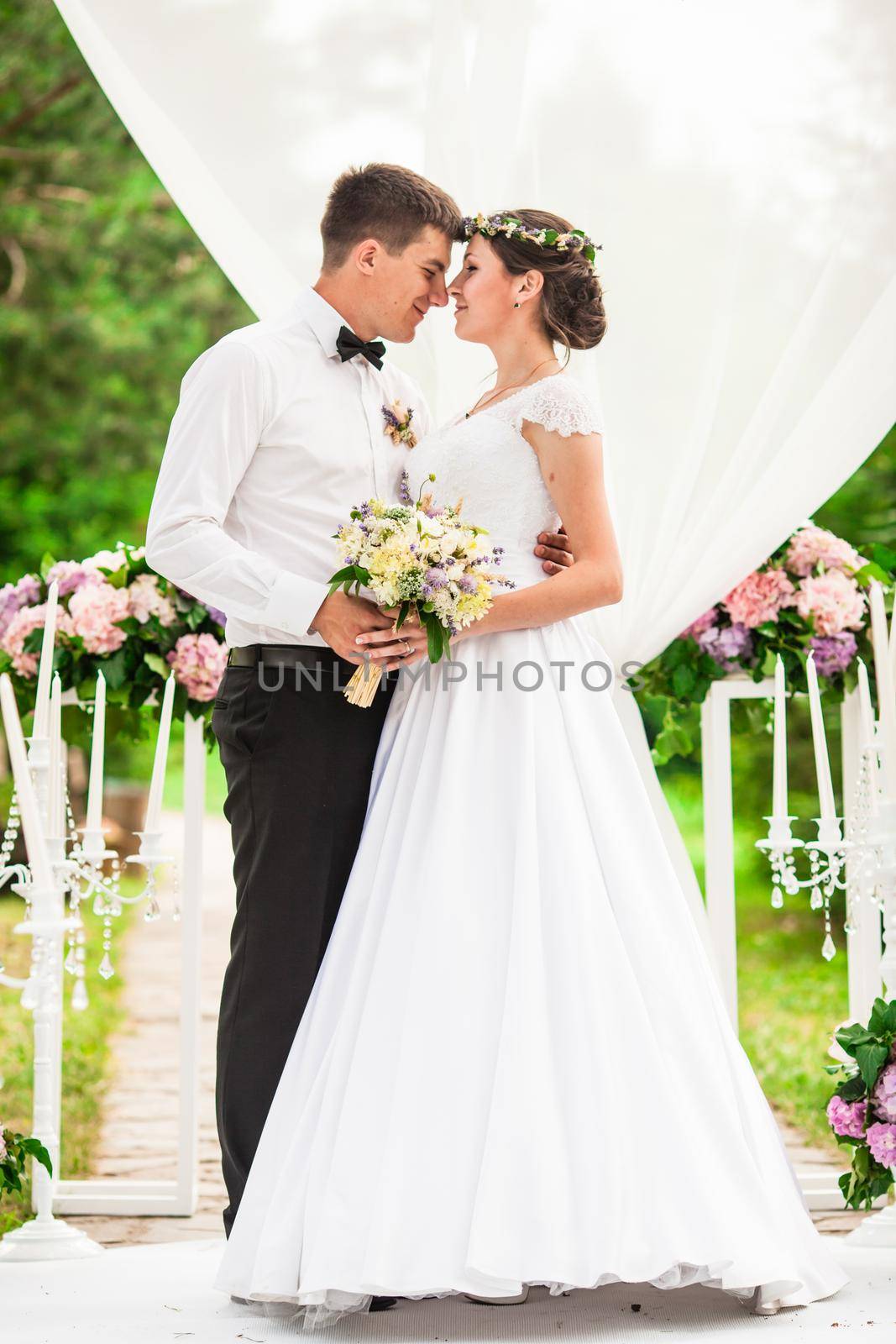 Wedding couple under the flower arch at the wedding ceremony by oksix