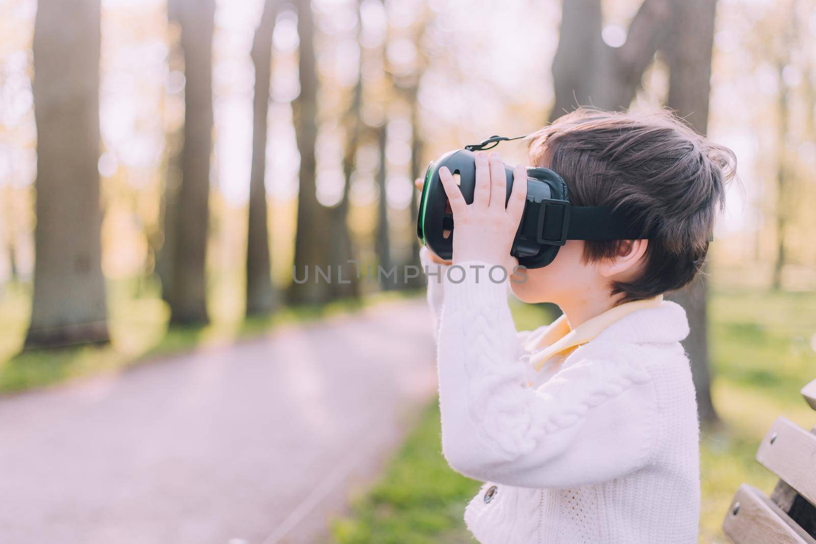 A boy is playing virtual reality glasses on the street . Modern gadgets. Children's games. The choice of virtual glasses. An article about virtual glasses. Modern children. Copy Space