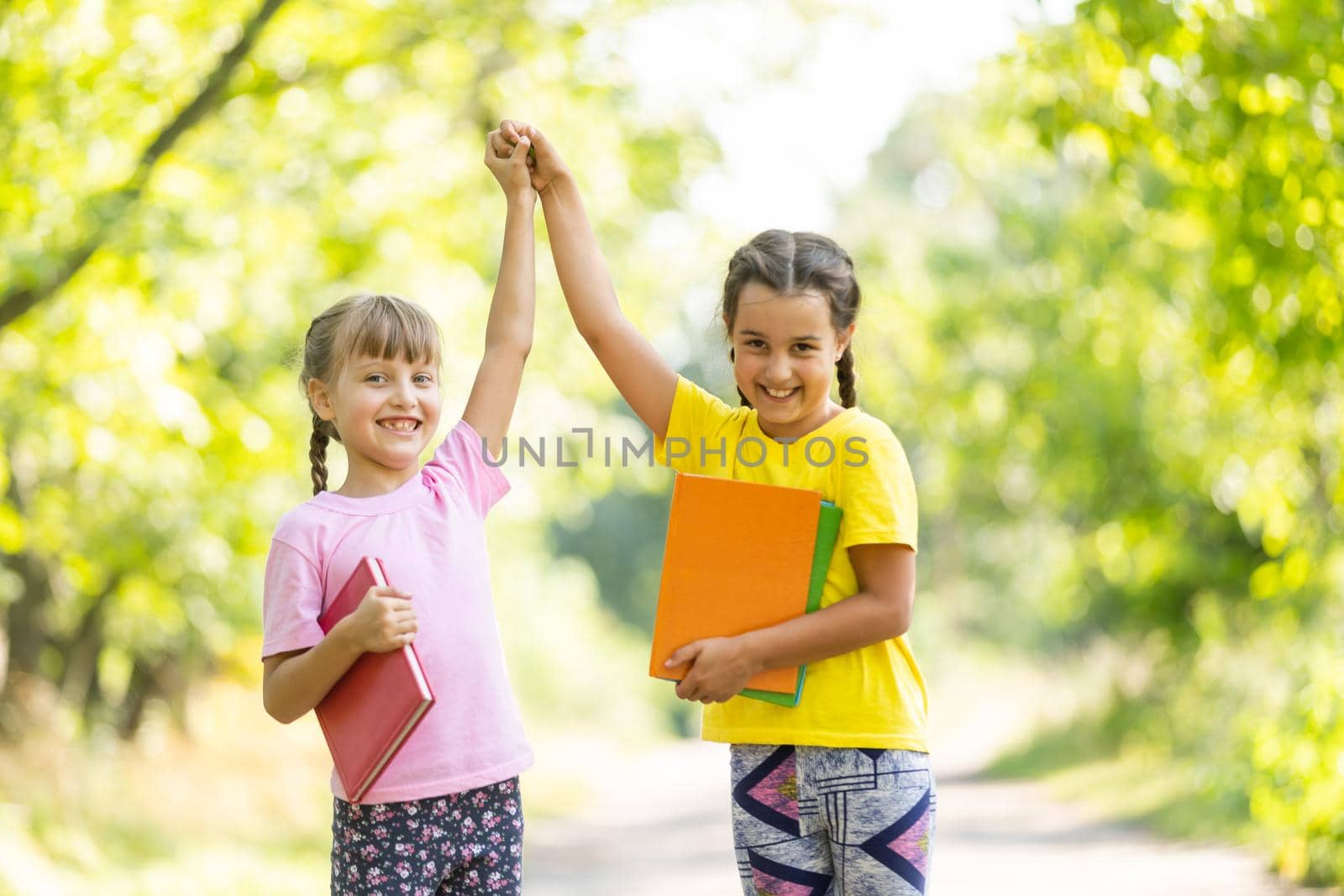 Two happy girls walking and talking each other in a campus.