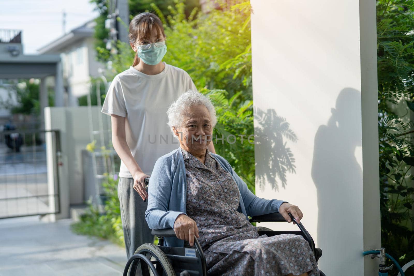 Caregiver help and care Asian senior or elderly old lady woman patient sitting on wheelchair to ramp in nursing hospital, healthy strong medical concept.