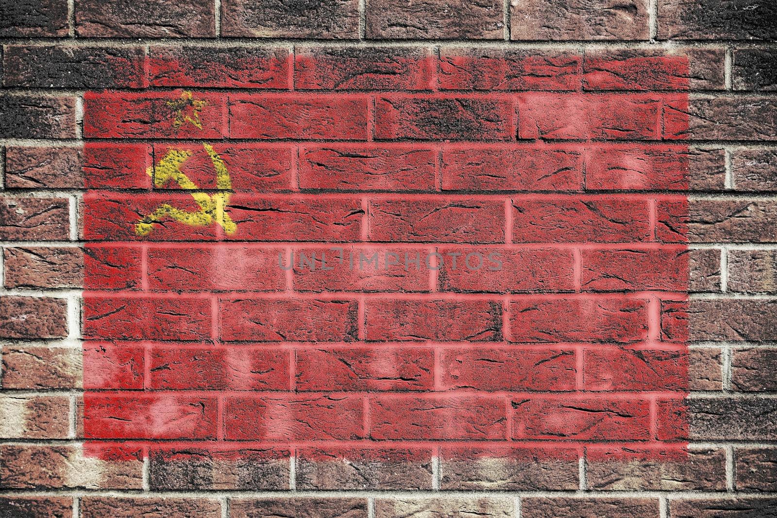 A USSR flag on a brick wall background red yellow hammer sickle CCCP