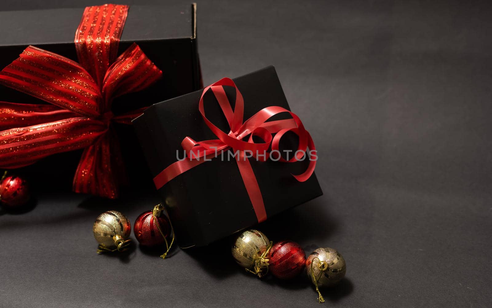 black gift box, balls, red Christmas decorations on the dark wooden background copy space.