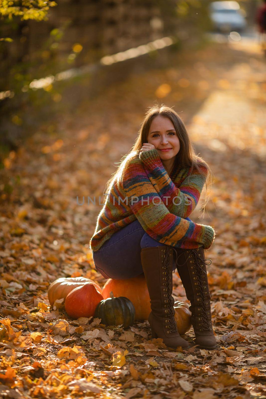 Smile woman sitting on the pumpkin on the autumanl maple leaves. Cozy autumn vibes Halloween, Thanksgiving day.