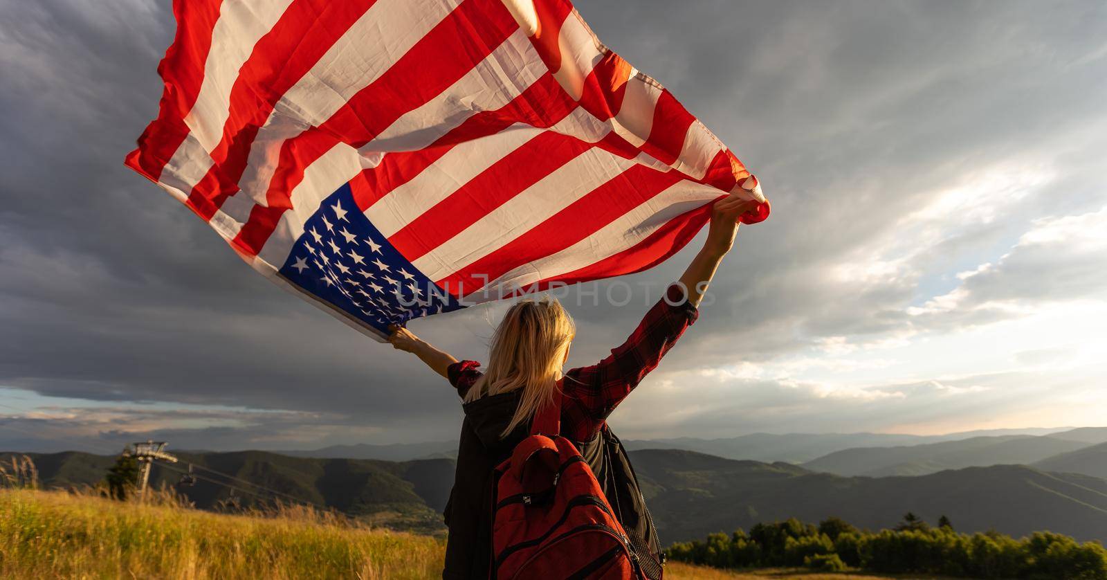 Young woman holding American flag on sky background by Andelov13