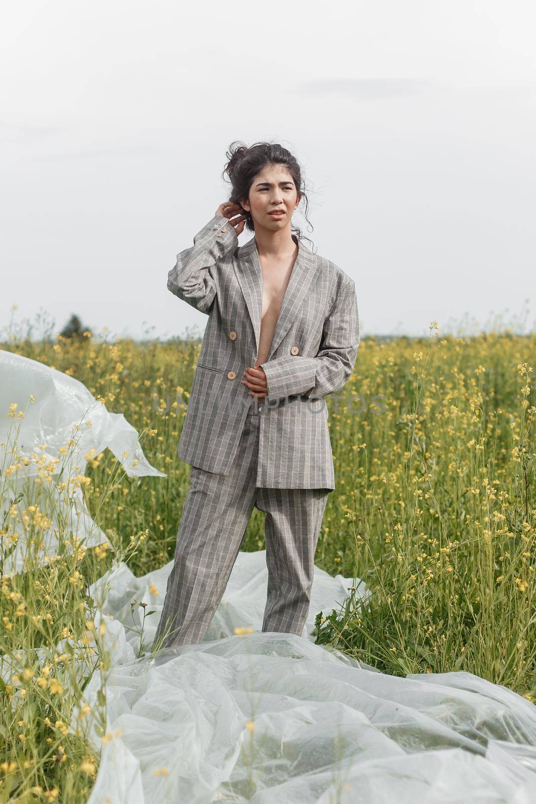 An Asian model poses in a field of yellow flowers for a clothing brand, polyethylene is the main props for a photo shoot. by Annu1tochka