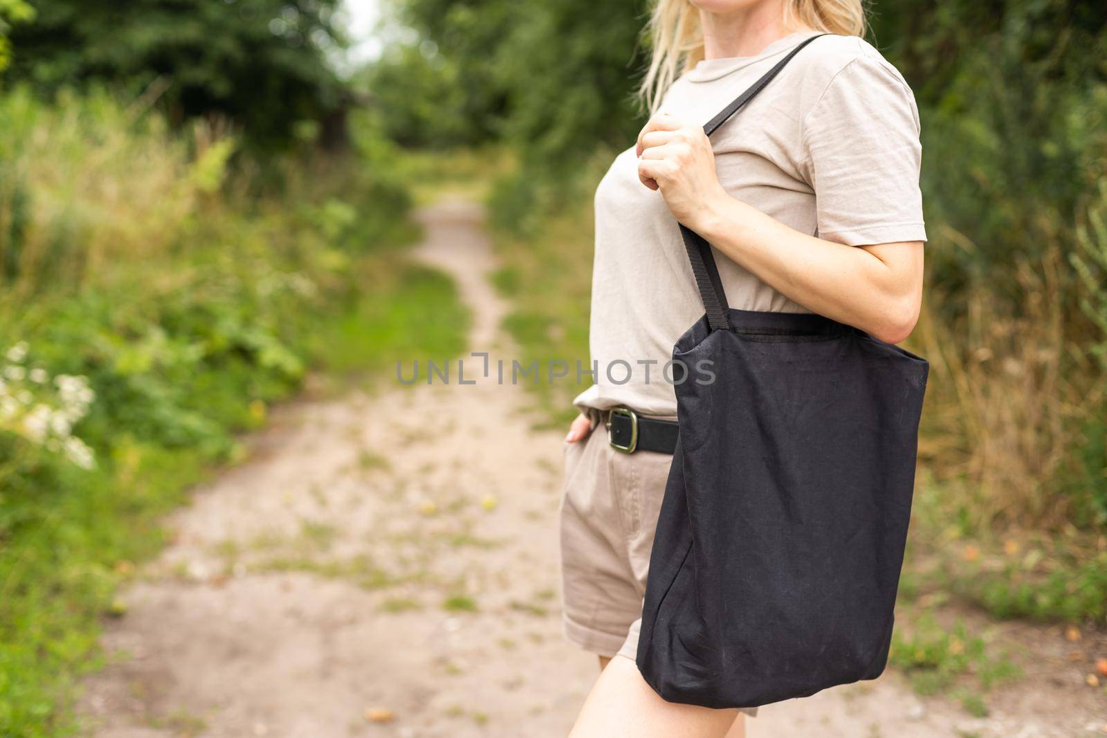 Girl is holding black cotton eco tote bag, design mockup by Andelov13