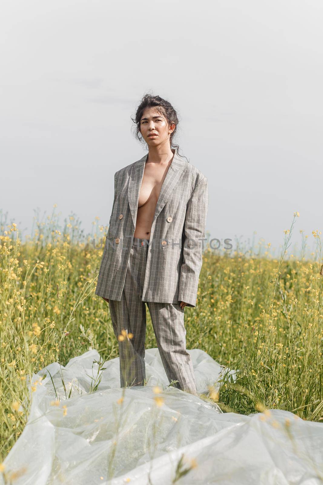 An Asian model poses in a field of yellow flowers for a clothing brand, polyethylene is the main props for a photo shoot. by Annu1tochka