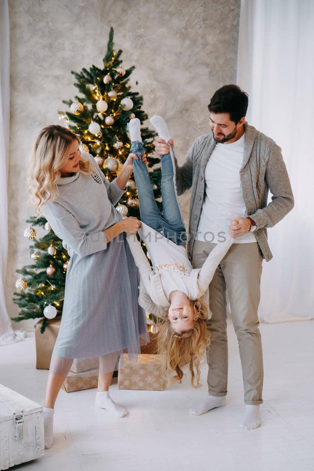 Happy family: mom, dad and pet. Family in a bright New Year's interior with a Christmas tree.