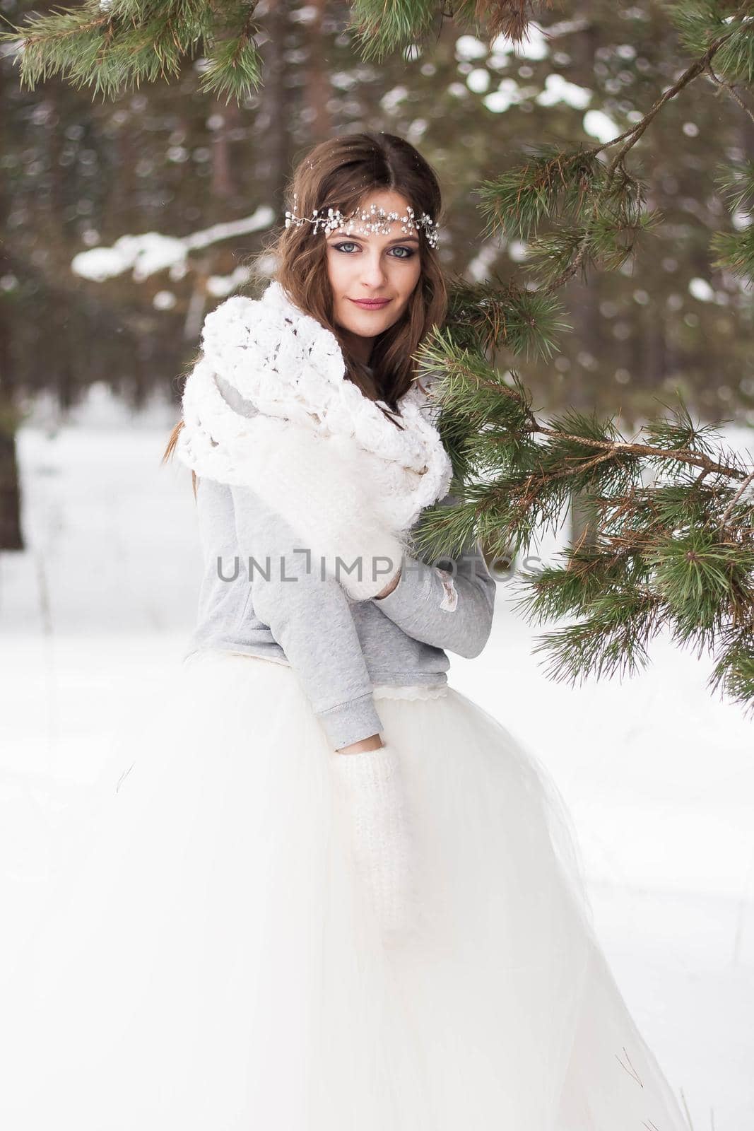 Beautiful bride in a white dress with a bouquet in a snow-covered winter forest. Portrait of the bride in nature.Beautiful bride in a white dress with a bouquet in a snow-covered winter forest. Portrait of the bride in nature.