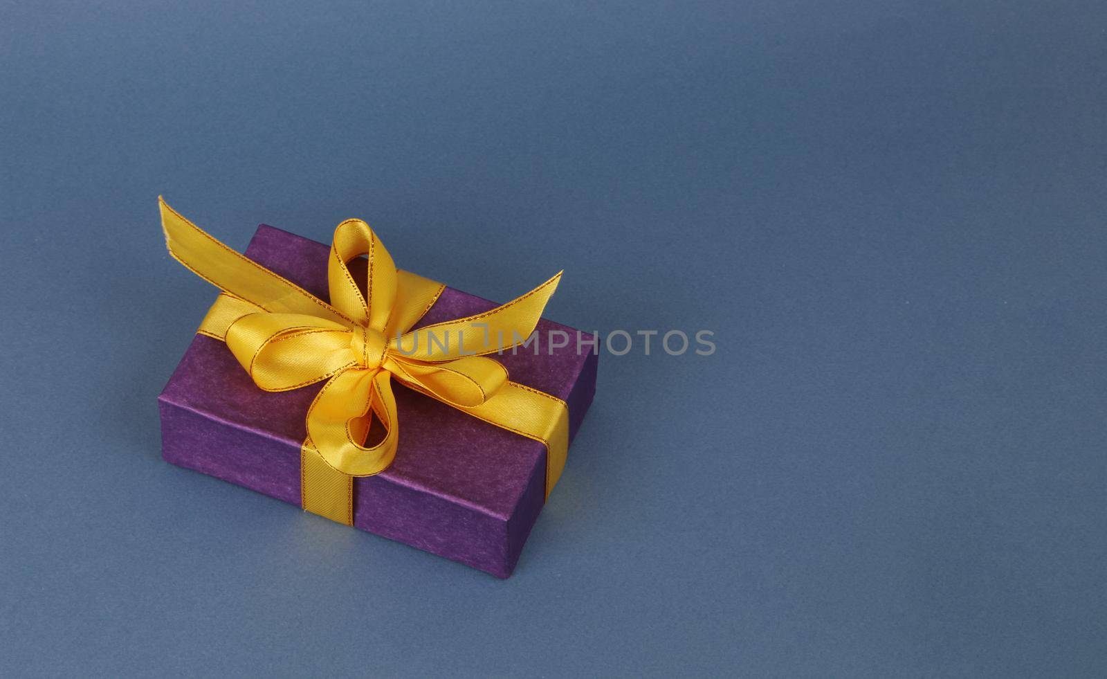 Purple gift box with a yellow bow on a blue background. by gelog67