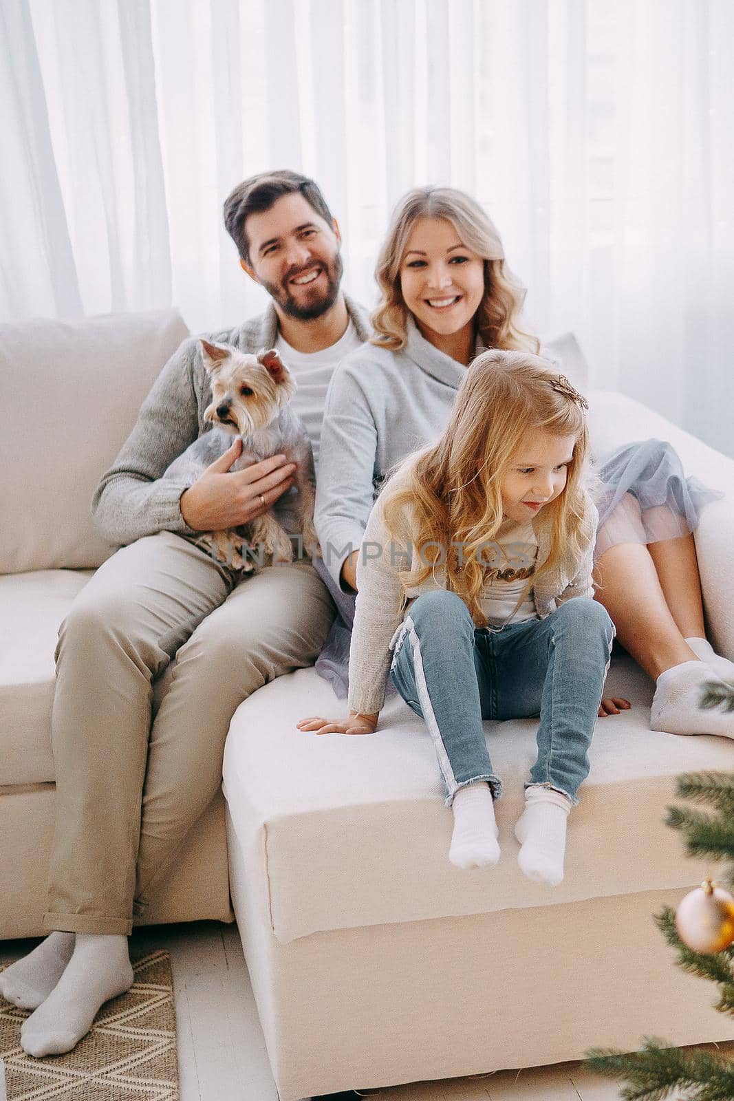 Happy family: mom, dad and pet. Family in a bright New Year's interior with a Christmas tree.