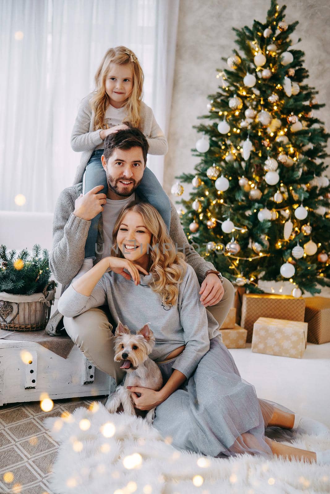 Happy family: mom, dad and pet. Family in a bright New Year's interior with a Christmas tree by Annu1tochka