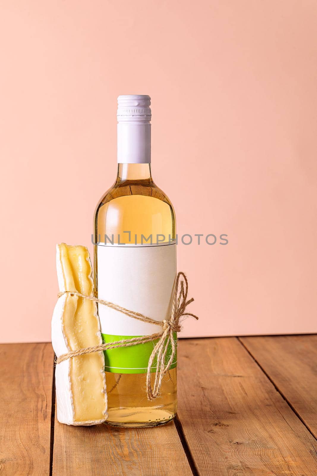 A bottle of white wine with a tied piece of cheese. Suitable food concept, couple. Creative