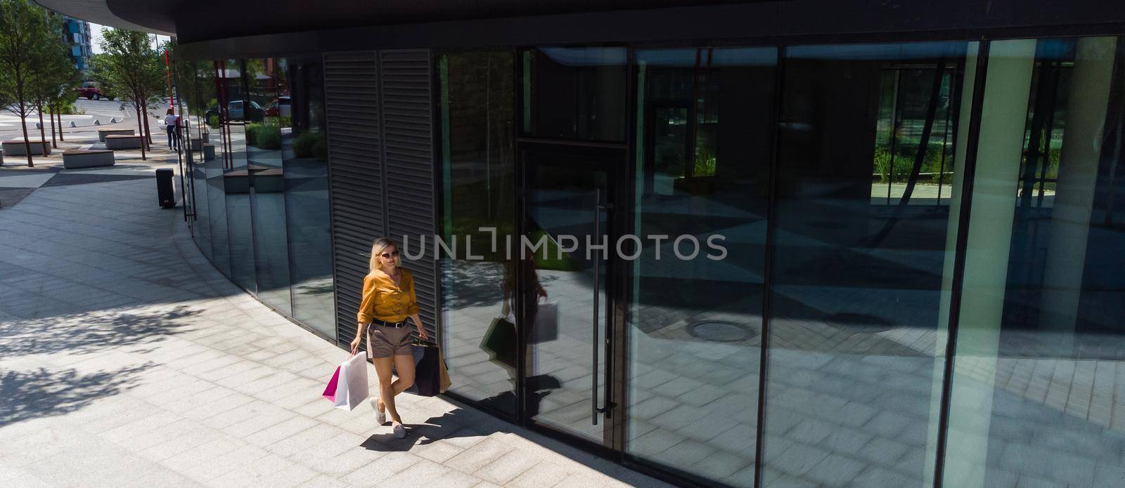 happiness, consumerism, sale and people concept - smiling young woman with shopping bags over mall background.