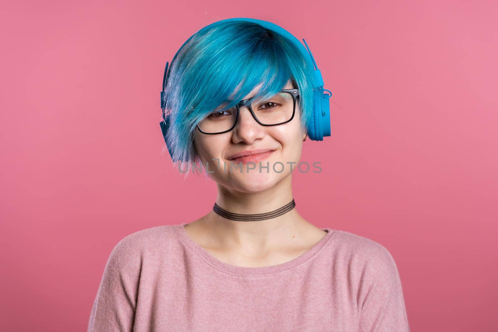 Pretty young girl with turquoise hair having fun, smiling, dancing with blue headphones in studio on colorful background. Music, dance, radio concept. by kristina_kokhanova