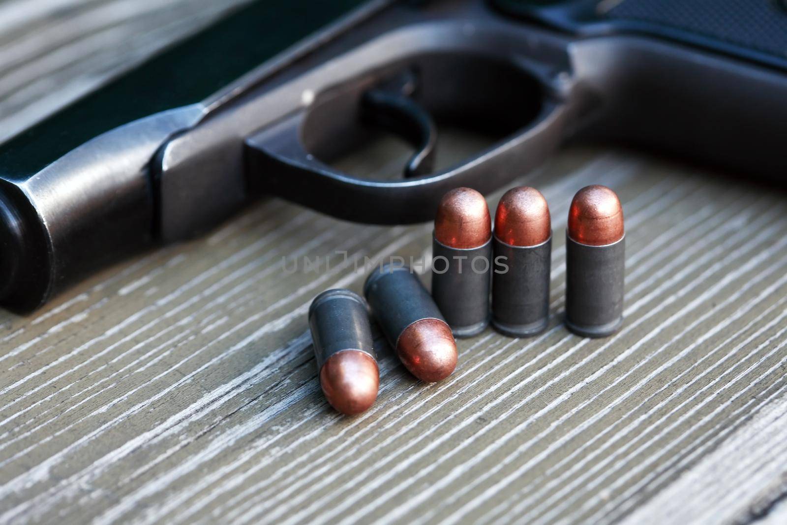 Handgun cartridges closeup on old wooden background near pistol