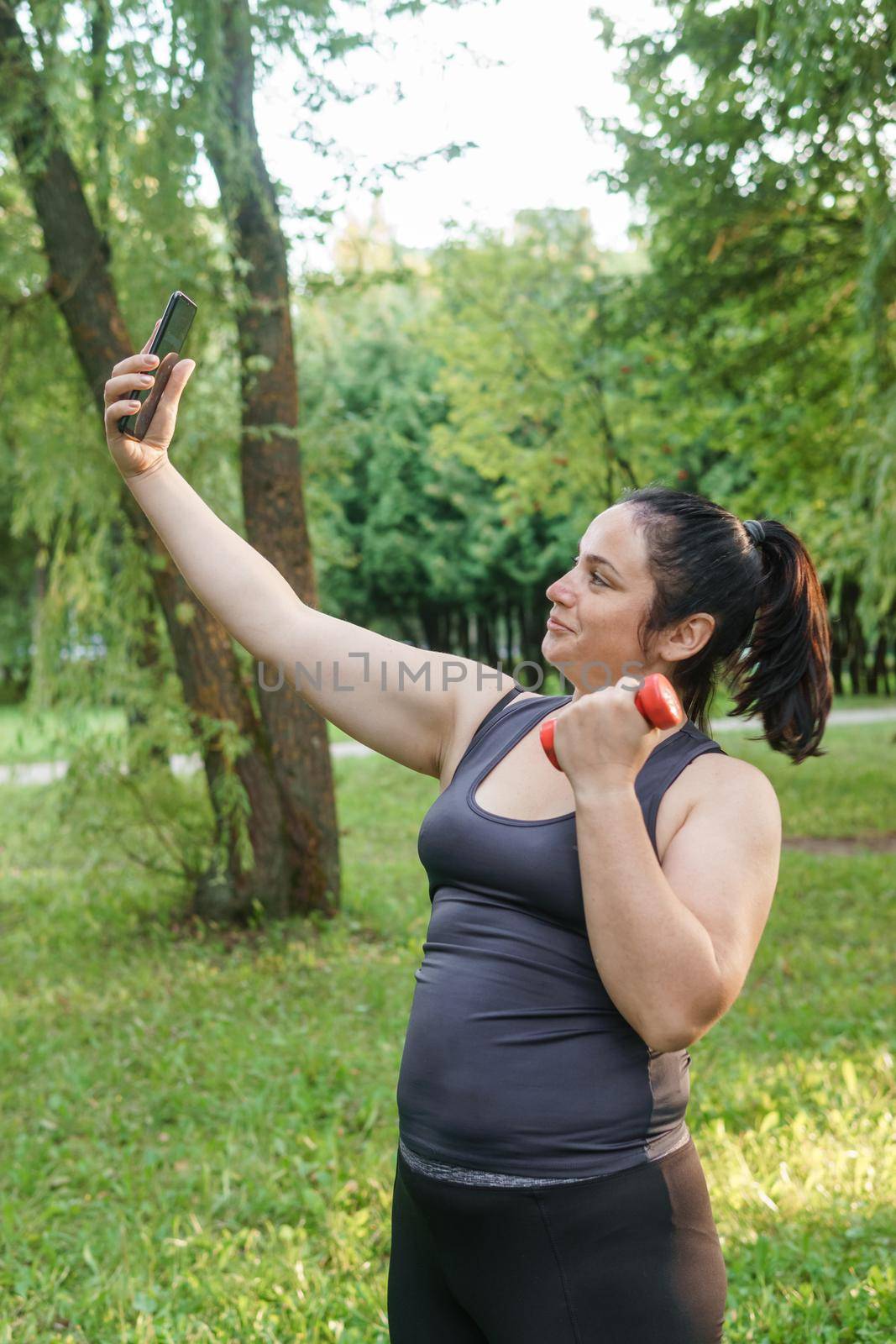 A charming brunette woman plus-size body positive practices sports in nature.