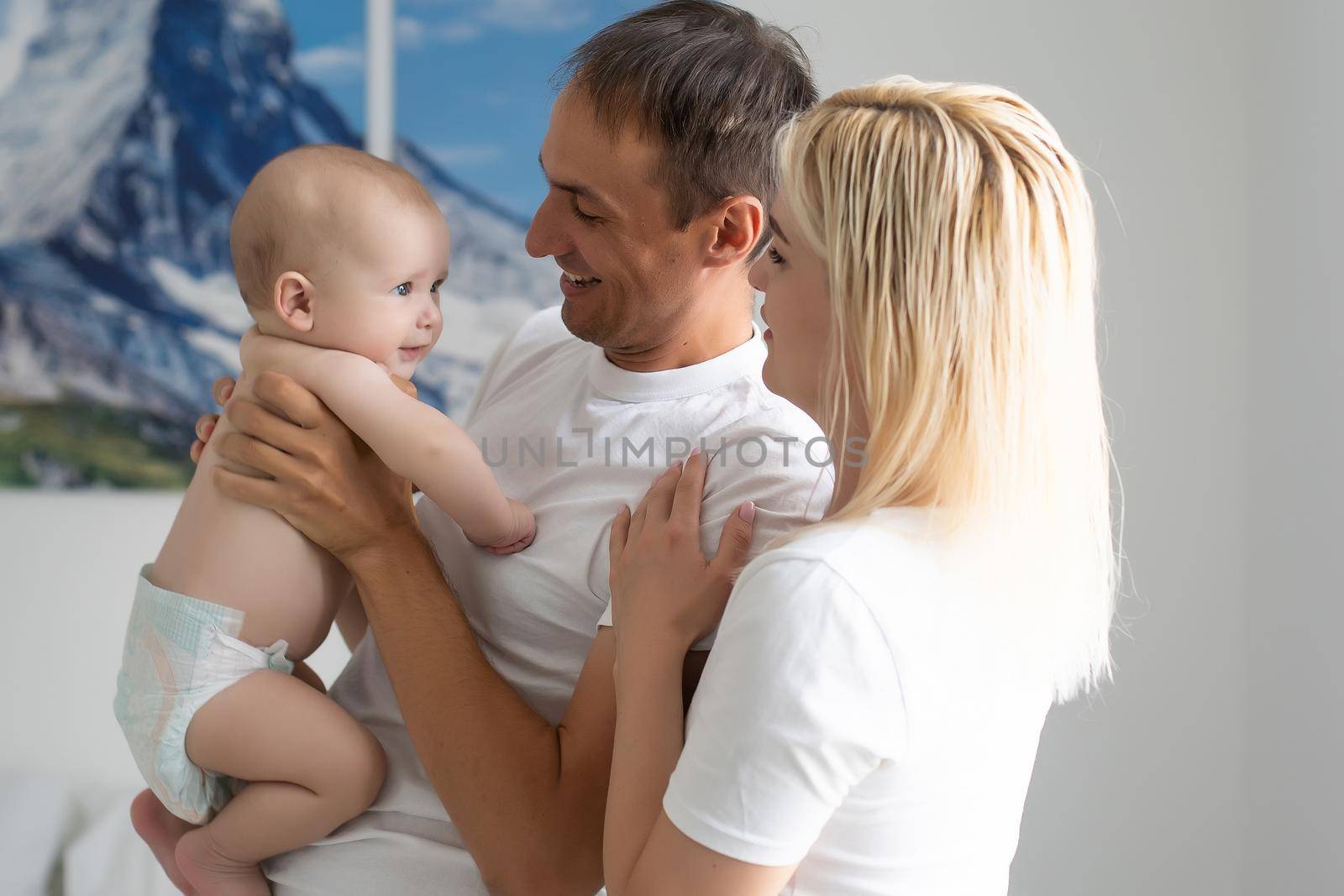 A Happy young family with baby in white bedroom by Andelov13