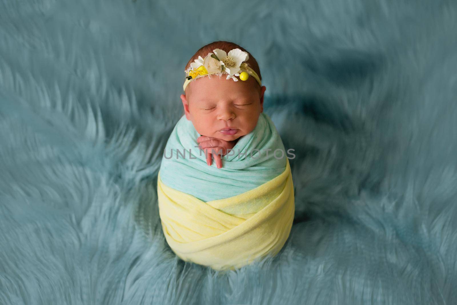 Ukrainian newborn child in the studio patriotic blue yellow colors during the war in Ukraine 2022. A little baby, girl sleeps in cocoon