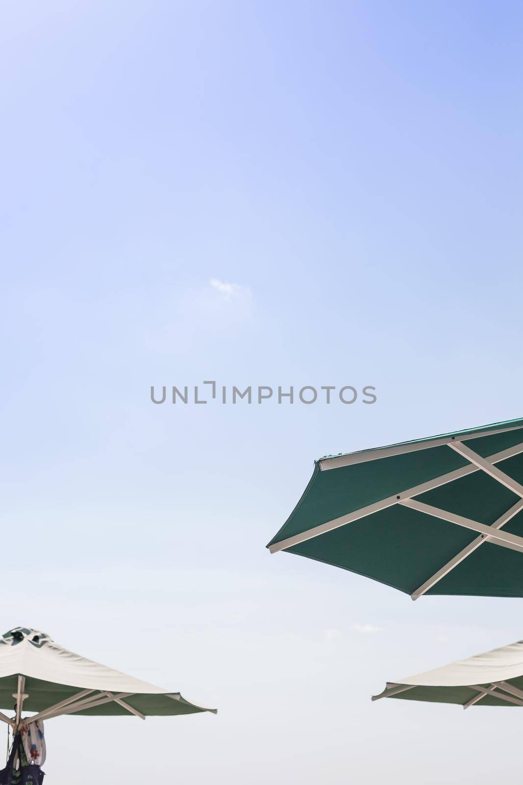 Sun blue and white open umbrella, comfortable rest by the ocean with personal beach parasol on beautiful cote dazur coastline, safe tan accessory, sunstroke protection