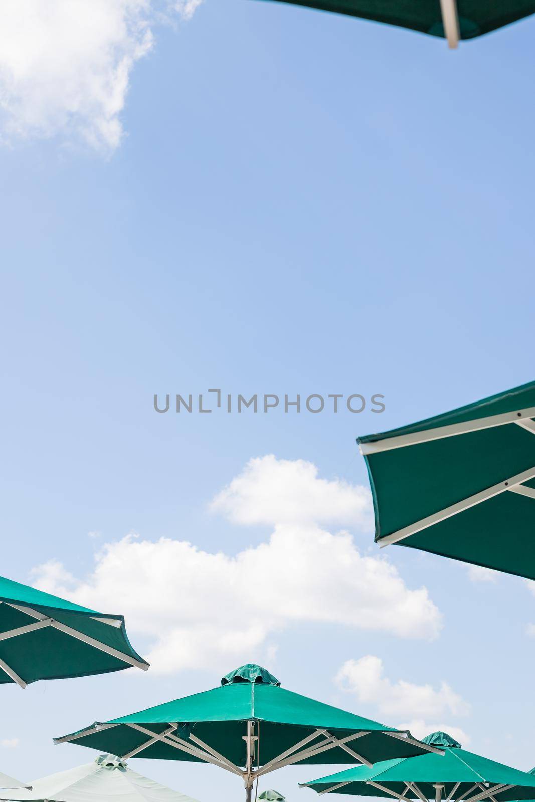 Several yellow umbrellas on the beach against blue sky with clouds in the summer