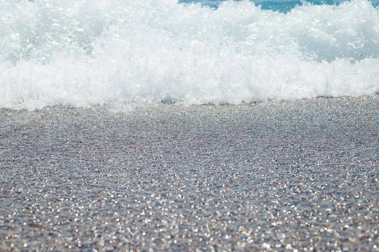 Pebble beach with azure sea water texture background