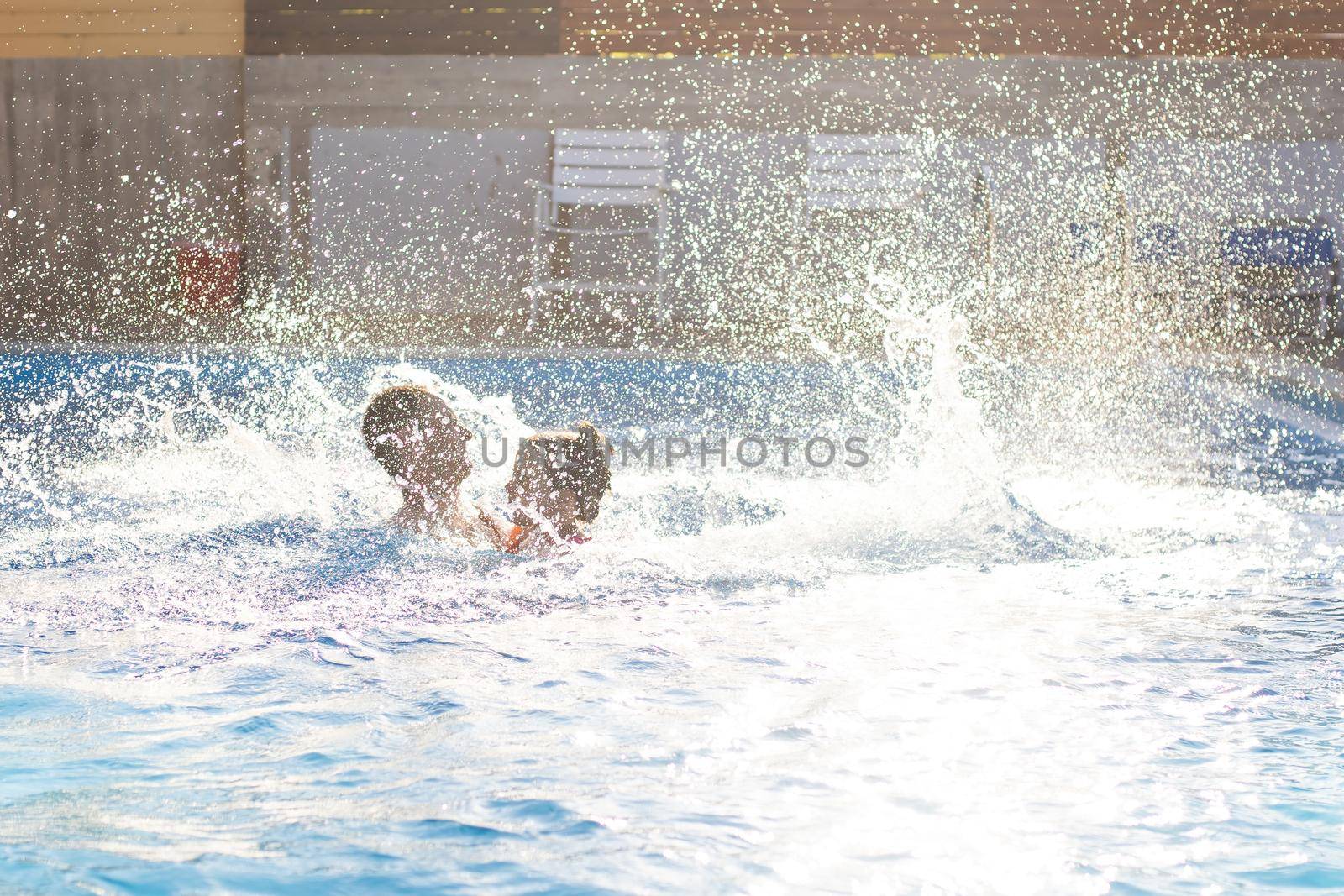 father catches little girl jumping in pool against sea.