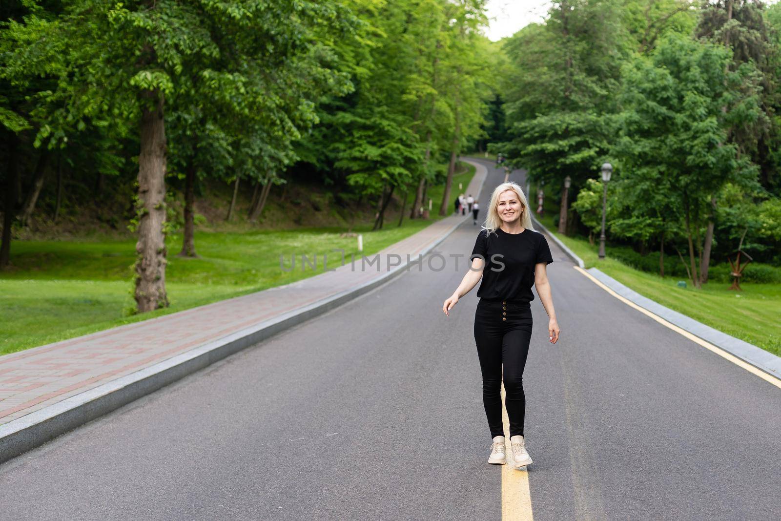 Attractive young woman walks along the line of the road enjoying nature. by Andelov13