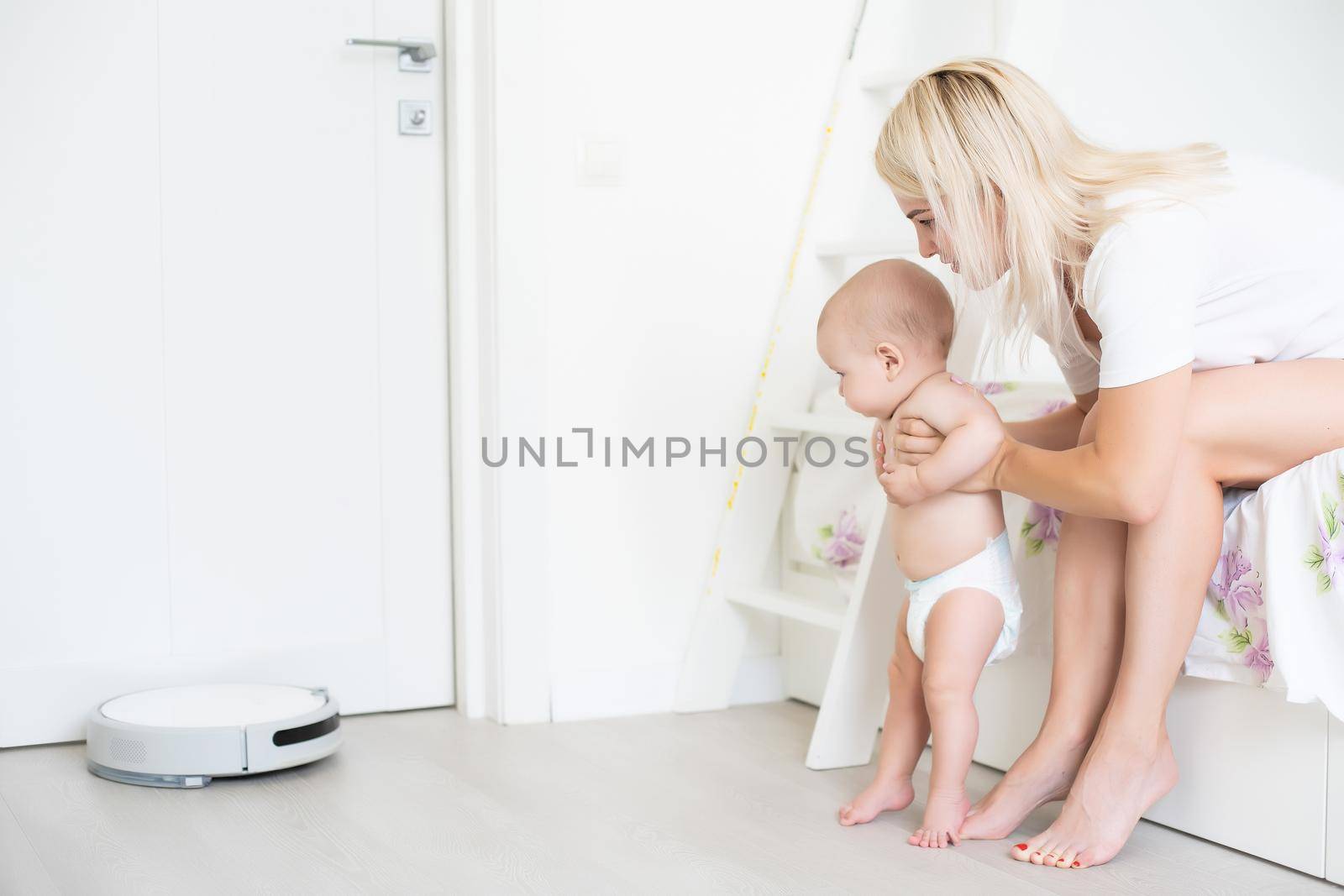 Little baby boy looks at the robotic vacuum cleaner at home