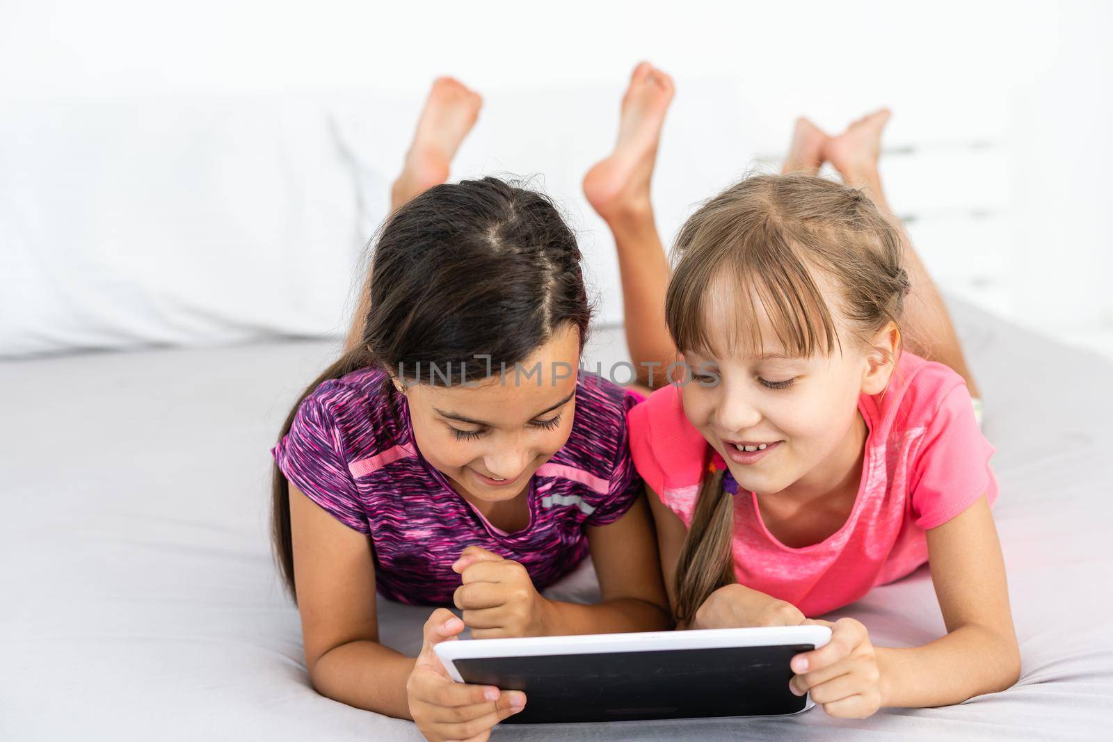 people, children, technology, friends and friendship concept - girls looking to tablet pc computers at home.