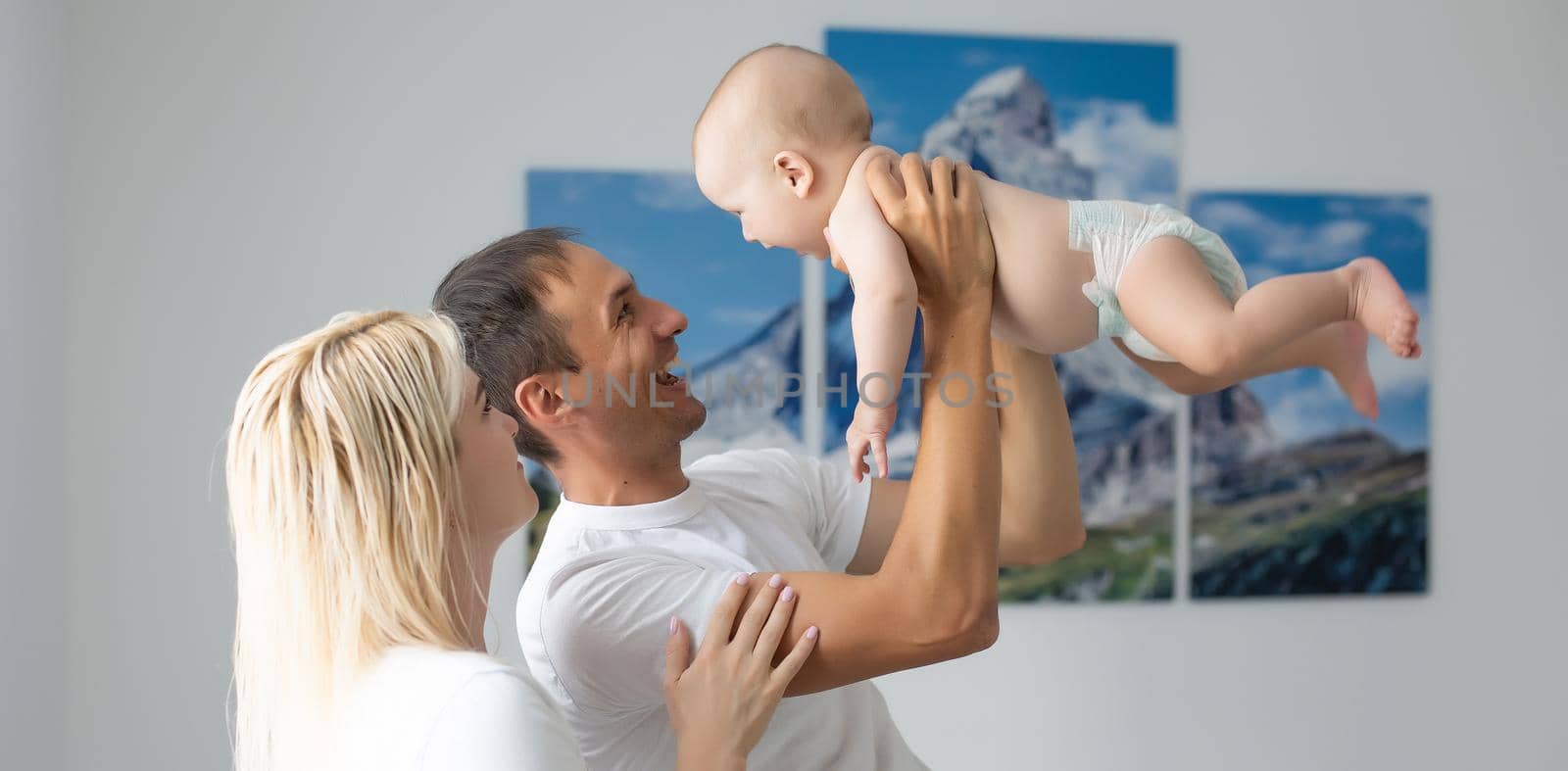 middle-aged parents with baby in white bedroom.
