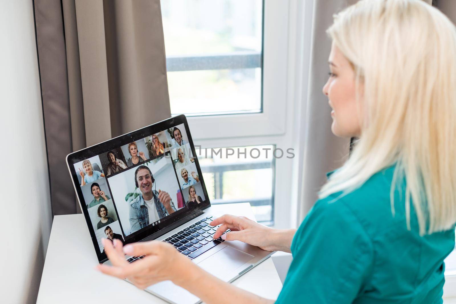 Cropped image of young woman using laptop for video conference at home.