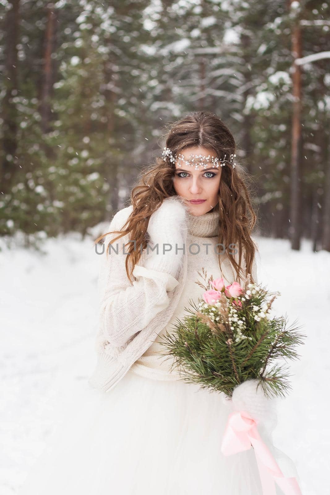 Beautiful bride in a white dress with a bouquet in a snow-covered winter forest. Portrait of the bride in nature.Beautiful bride in a white dress with a bouquet in a snow-covered winter forest. Portrait of the bride in nature.