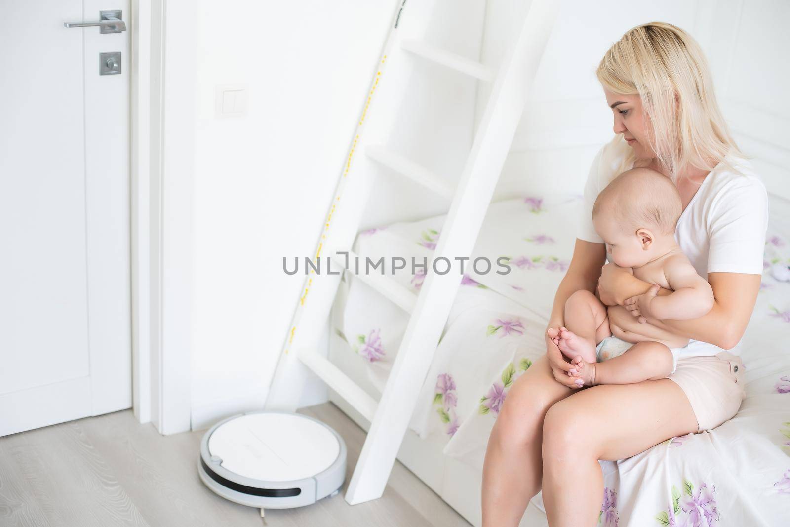 Little baby boy looks at the robotic vacuum cleaner at home