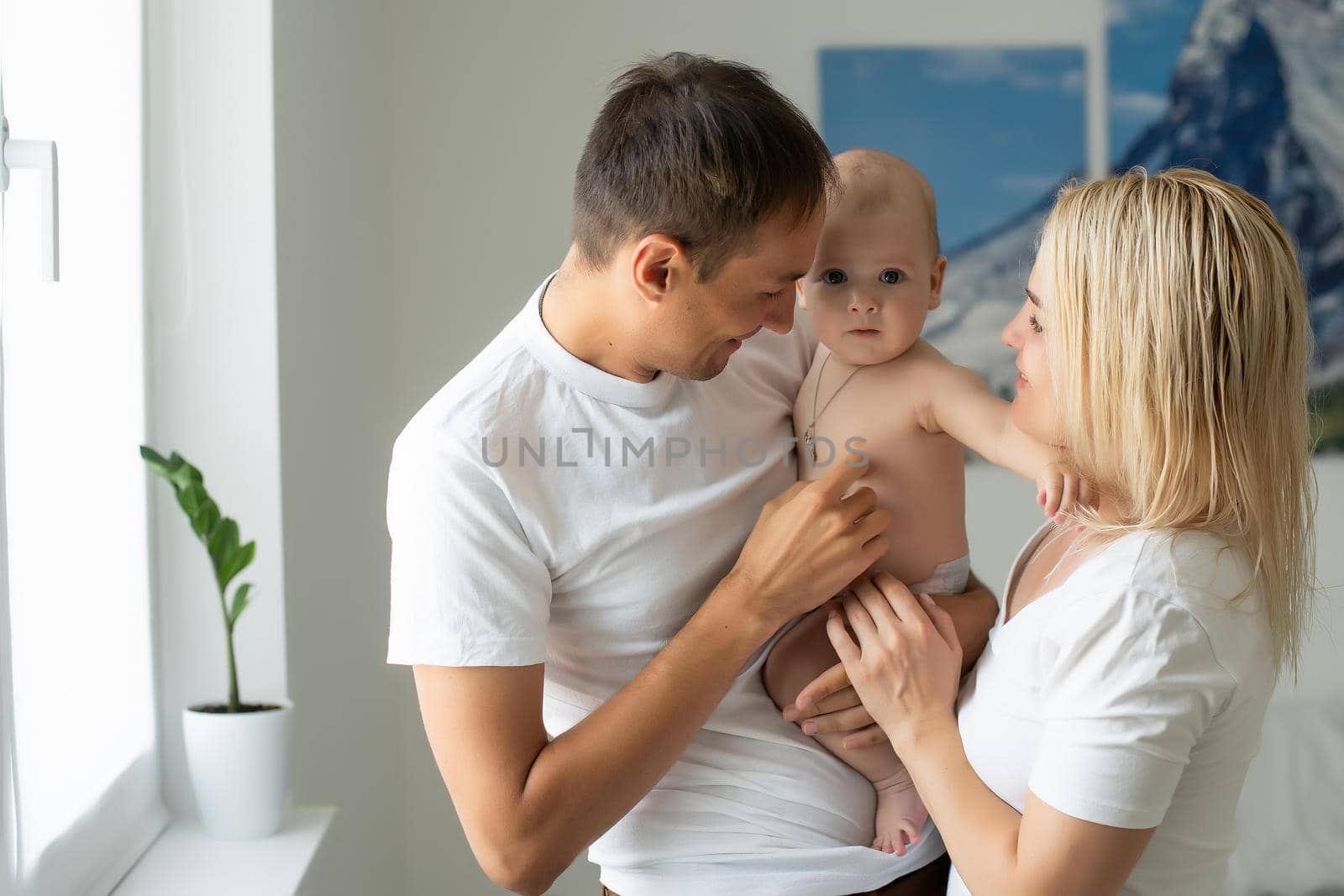 Portrait of happy young parents with baby at home.