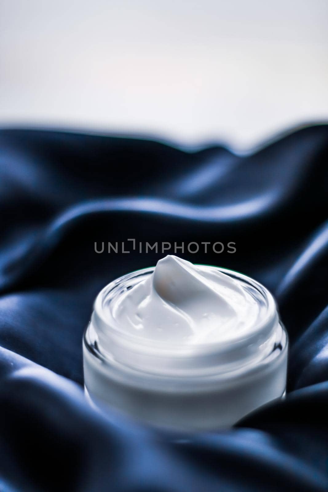 Beauty, anti-age cosmetics and skincare concept - Luxury face cream jar on a dark blue silk