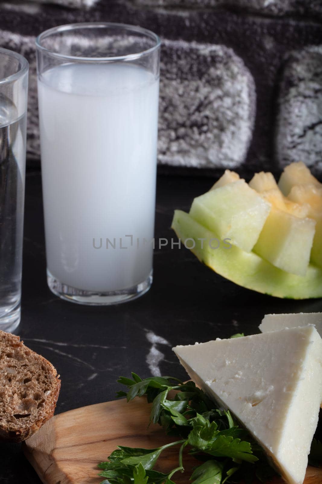 Turkish Raki with water on table with sliced melon and appetizer, traditional Turkish alcohol known as Raki, chill with friends at restaurant, dinner idea, eating and drinking concept, sitting view by senkaya