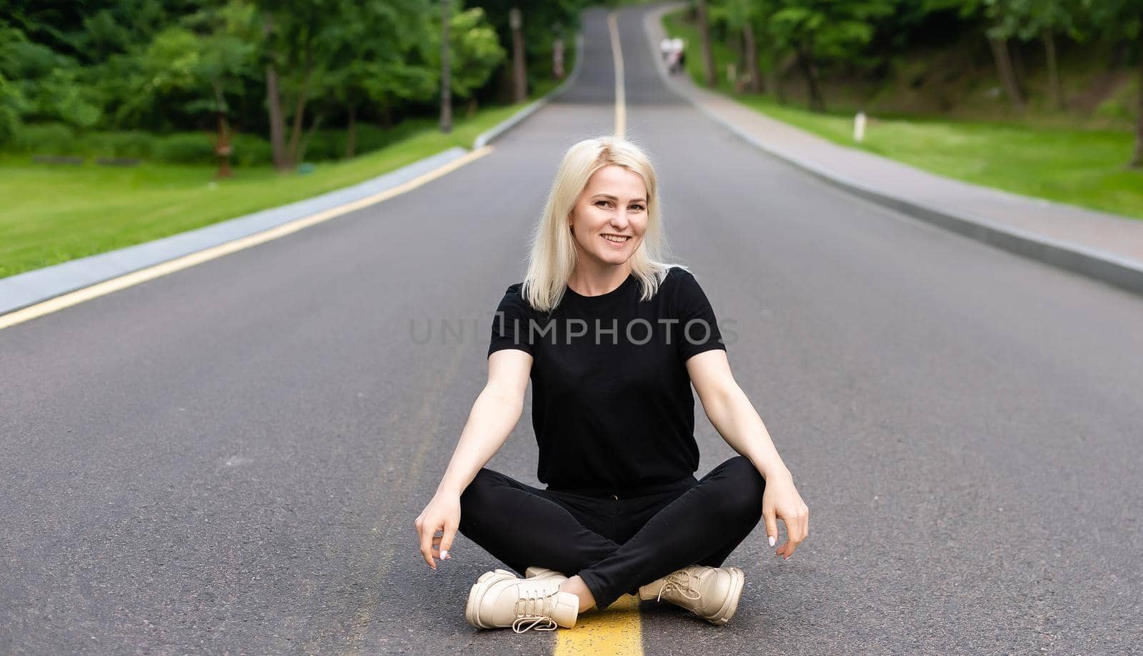 pretty woman sitting in the middle of a street with bare feet.