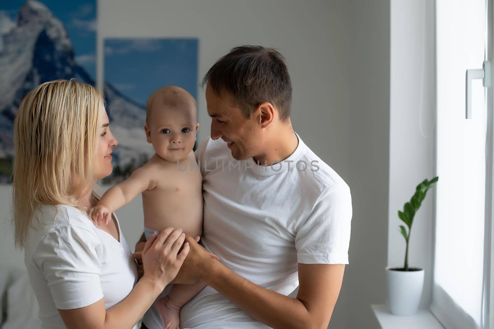 middle-aged parents with baby in white bedroom.