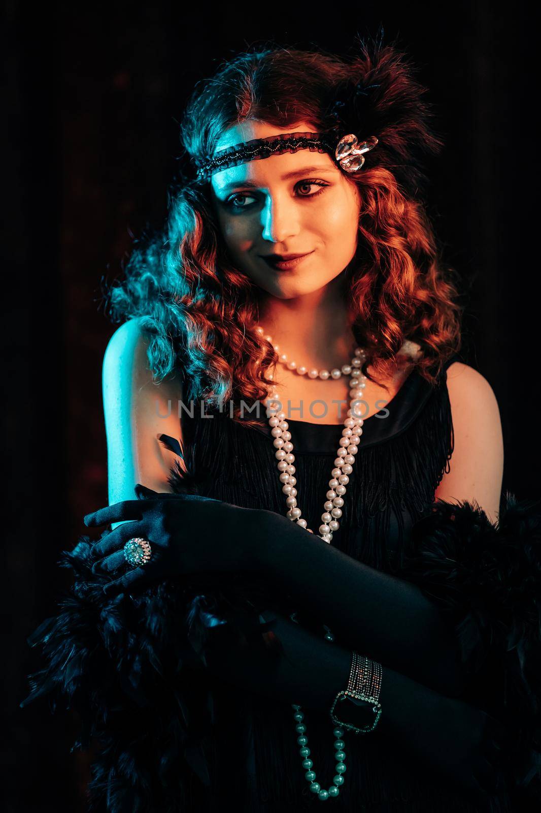 Portrait of vintage styled red haired woman dressed in Great Gatsby era flirting and posing on velours background. Roaring twenties, retro, party, fashion concept. High quality photo