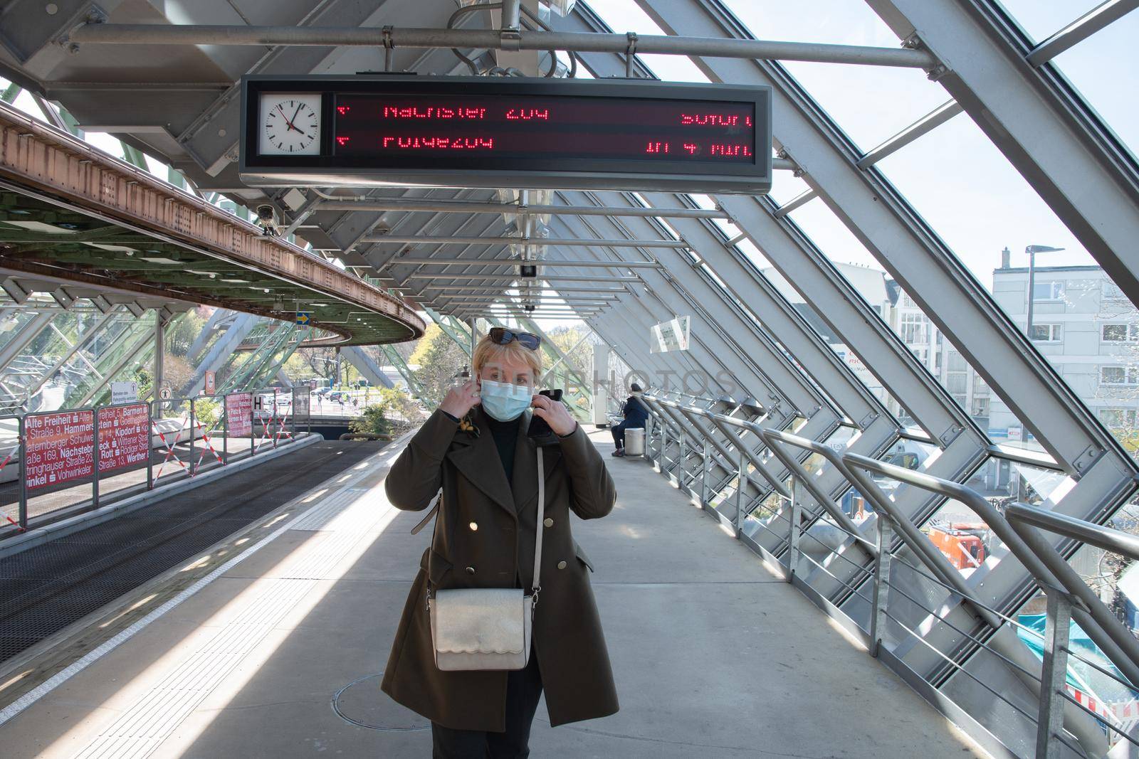 Middle-aged blonde woman waiting for a carriage on the Wuppertal suspension railway platform in Germany, The unique electric monorail system is an attraction. High quality photo