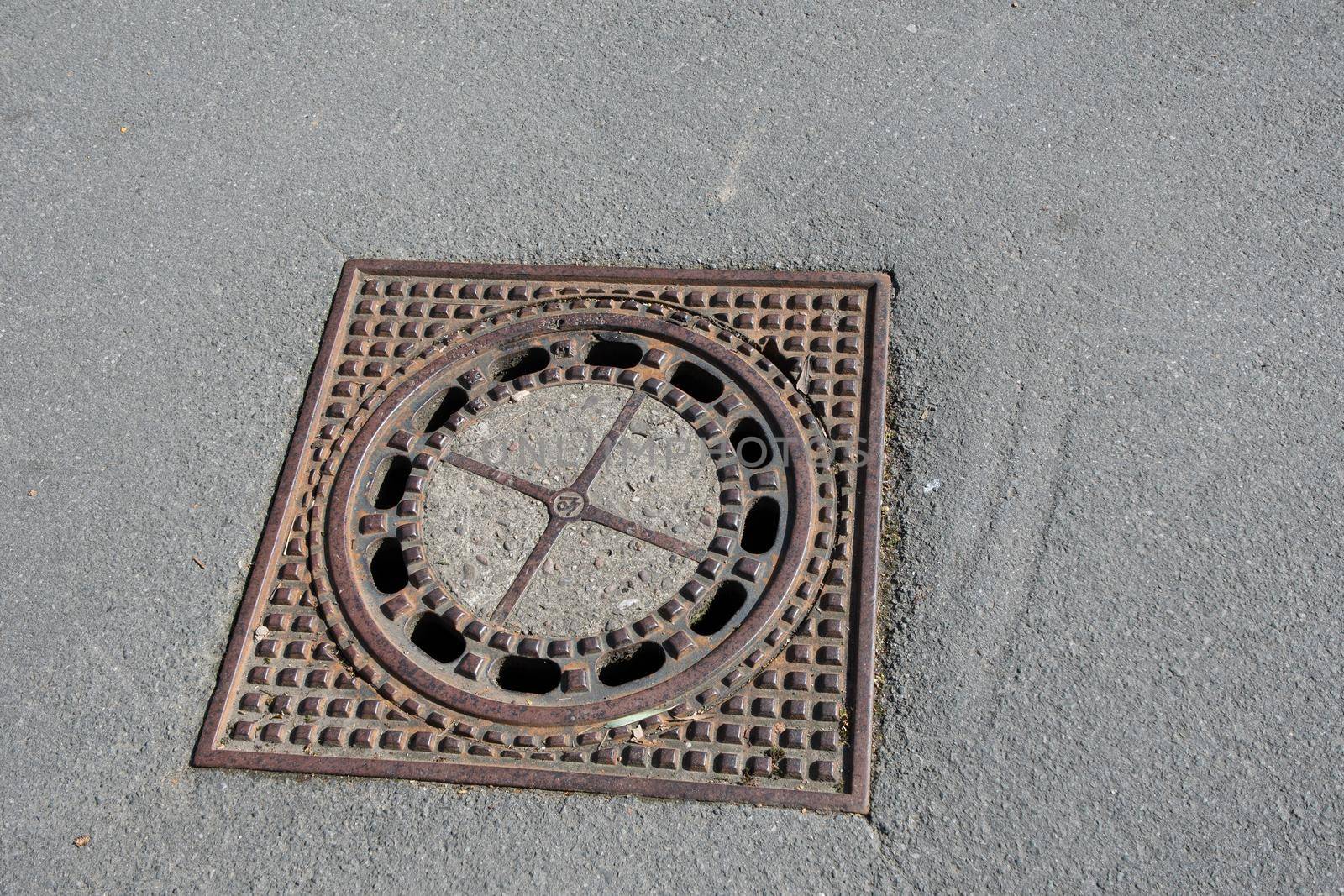 Old iron metal manhole cover sewer cap on the city street asphalt. High quality photo