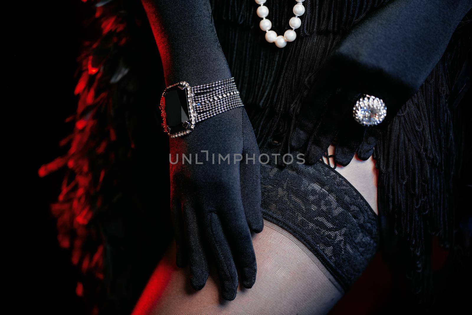 Old-fashioned woman dressed in style of Great Gatsby era shows her legs and adjusts nylon mesh stockings. Vintage, flapper party, retro fashion concept by kristina_kokhanova