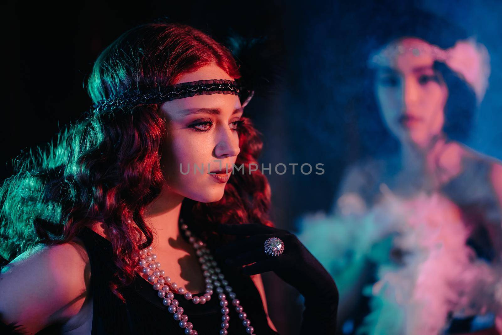 Portrait of young flapper women dressed in style of Great Gatsby posing on dark velours background. Roaring twenties, retro, party, fashion concept. High quality photo