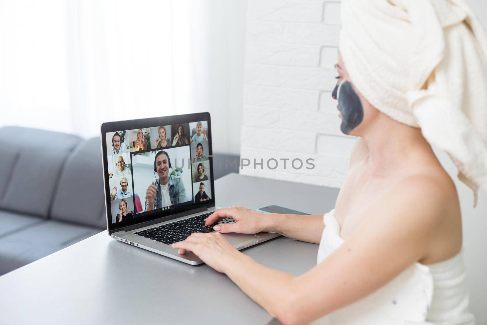 incredible pretty girl at home in pajamas made a cosmetic mask and works with a laptop. The concept of cosmetic mask on a girl