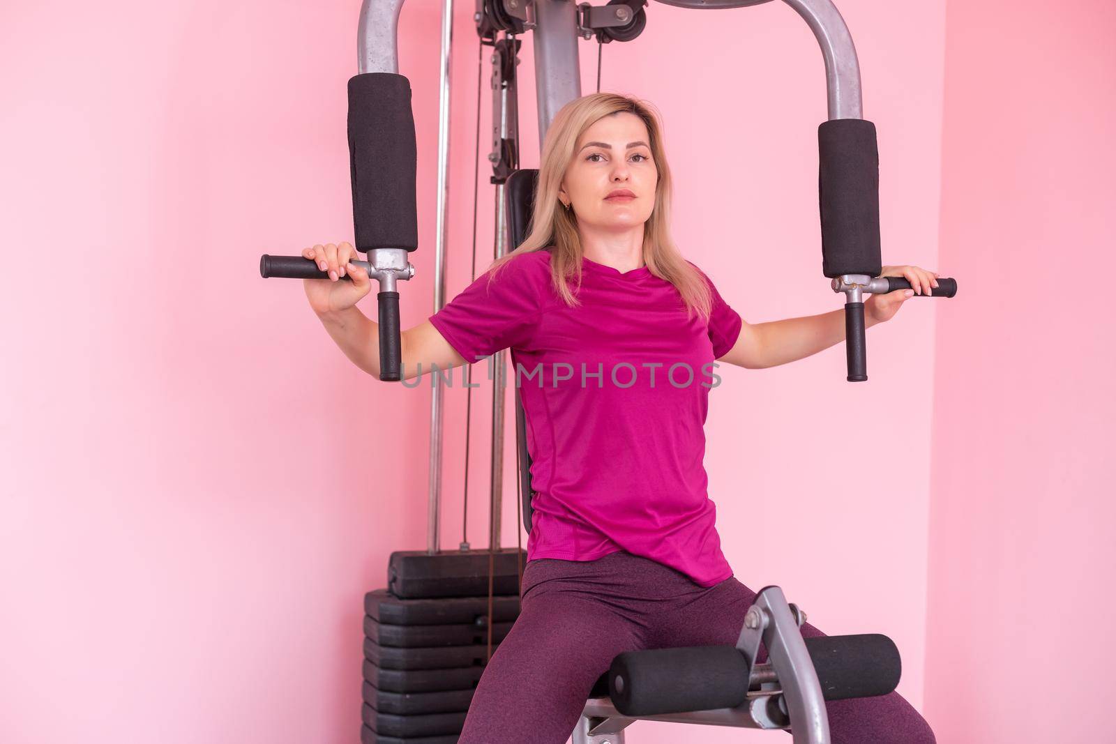 woman wearing pink and black professional sportswear pulling up at the gym. Strength and motivation concept