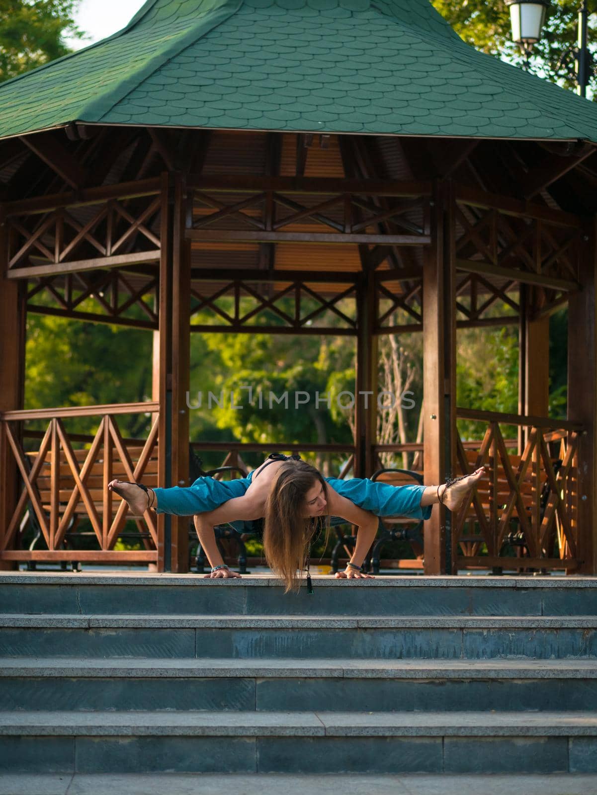 Girl's meditation on wooden alcove background. Morning yoga portrait of beautiful young woman wearing blue pants and top. Health care concept. by kristina_kokhanova