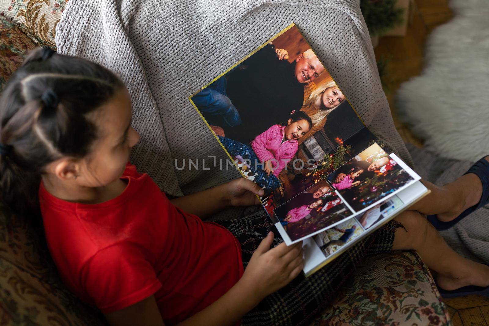 A Little Caucasian girl holding a photobook with her photographs in her hands.