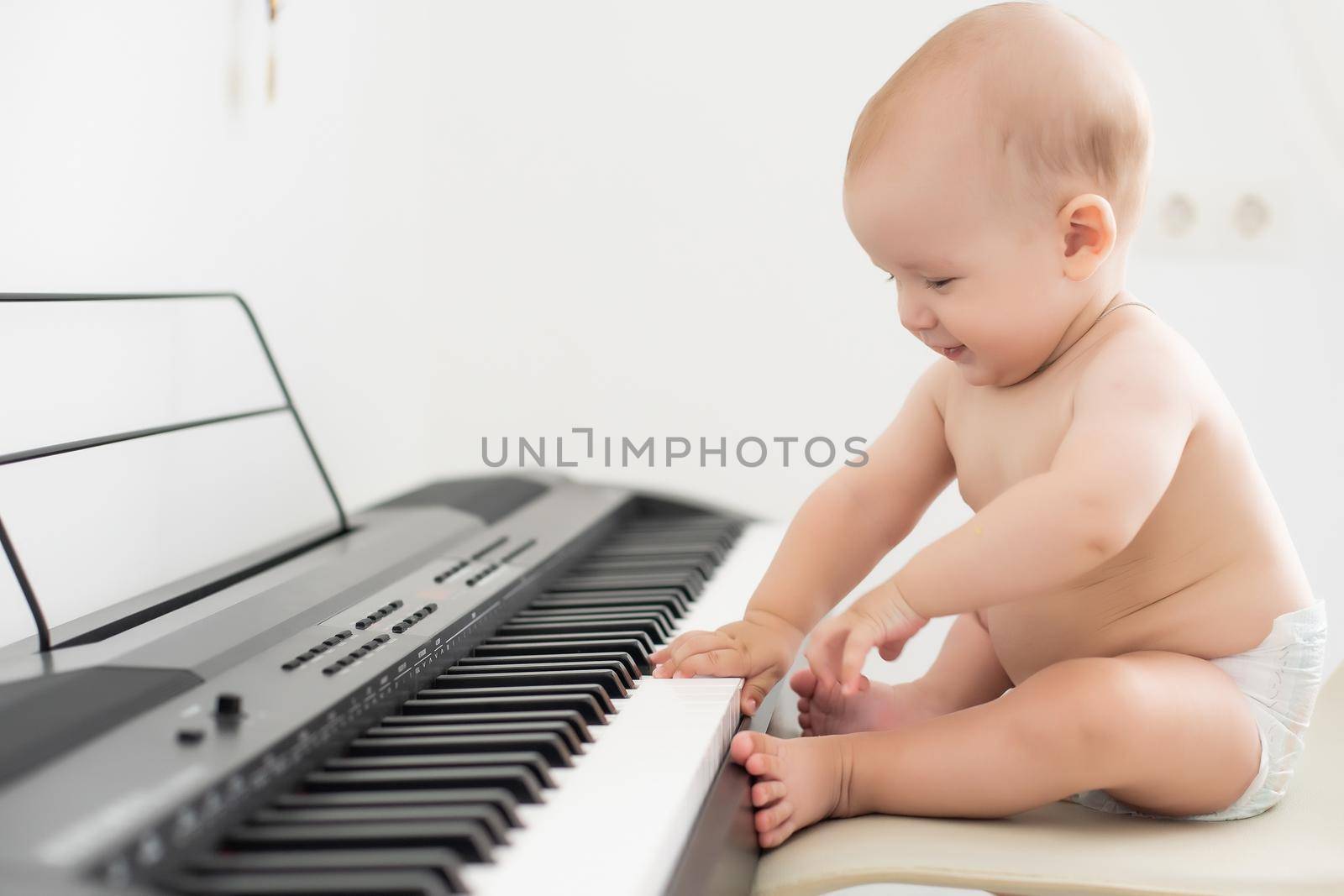 toddler baby boy, playing piano at home, child learning.